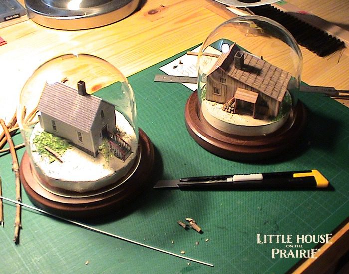 Globes of small models of the school house and Ingalls family home.