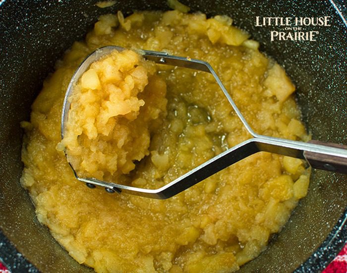 Crushing the spiced apples to make homemade applesauce like Laura Ingalls Wilder.